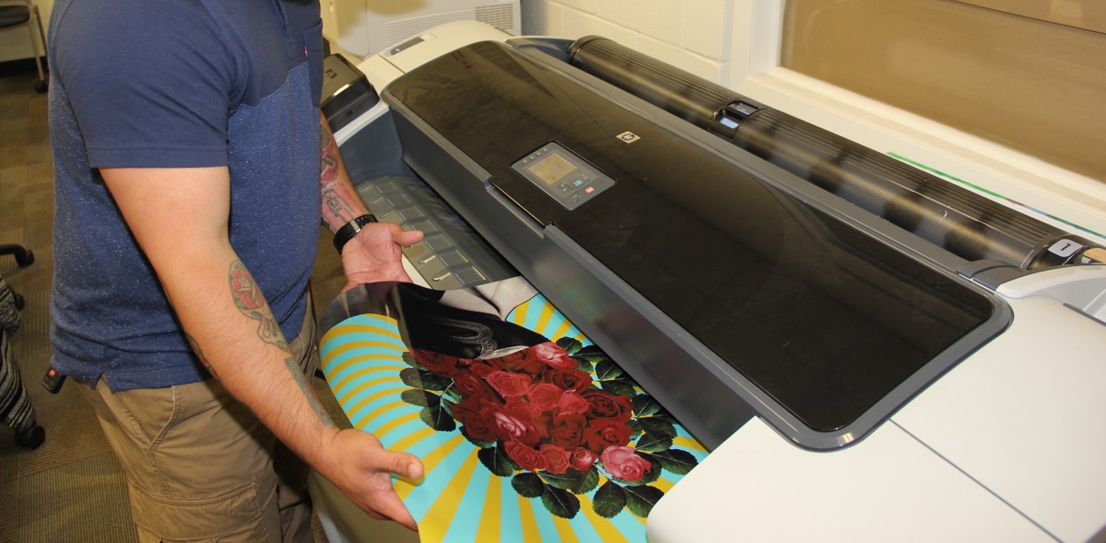 Student taking a banner from the printing machine